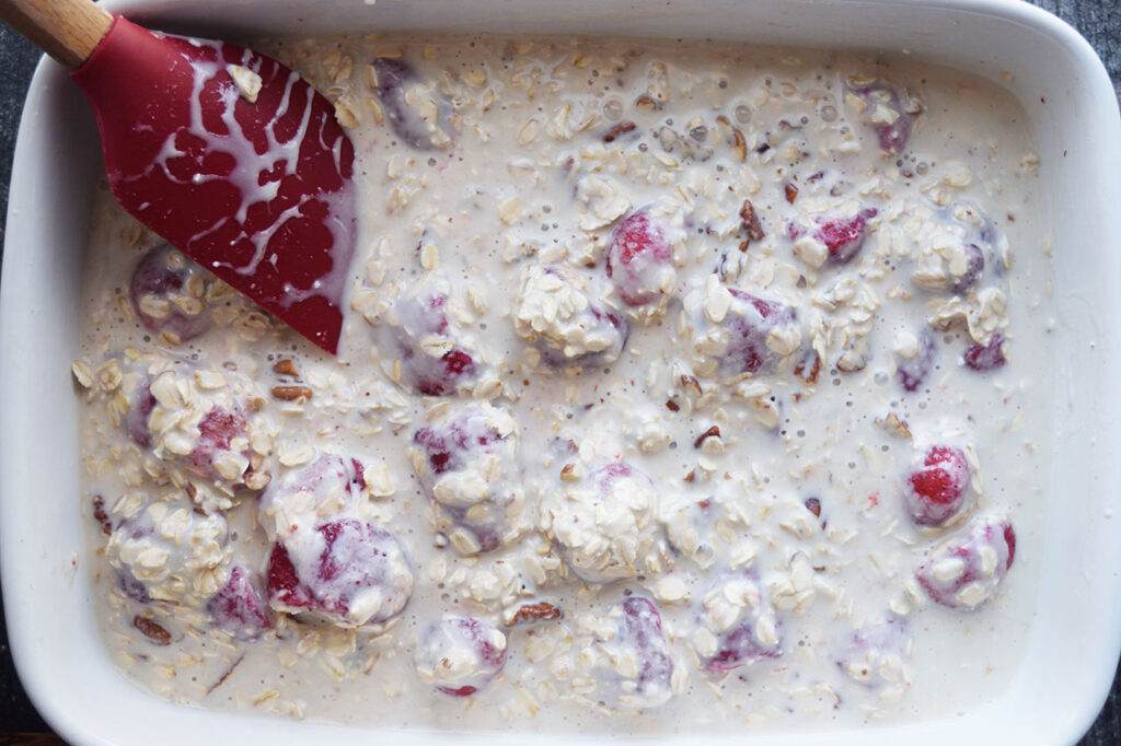 All the Baked Oatmeal With Strawberries Recipe ingredient mixed together in a white casserole dish.