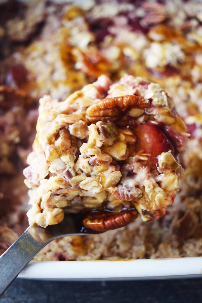 A spoonful of Baked Oatmeal With Strawberries over a casserole dish.