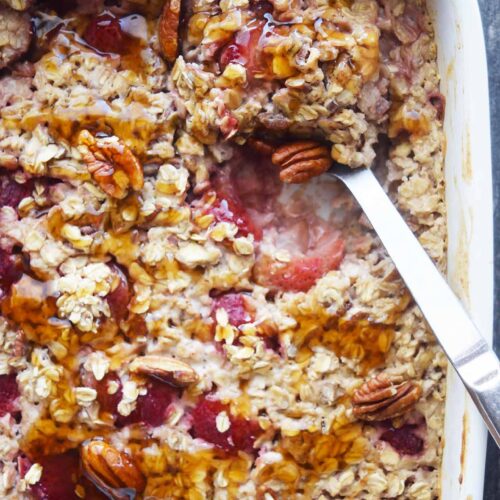 A serving spoon pushed into the Baked Oatmeal With Strawberries casserole.