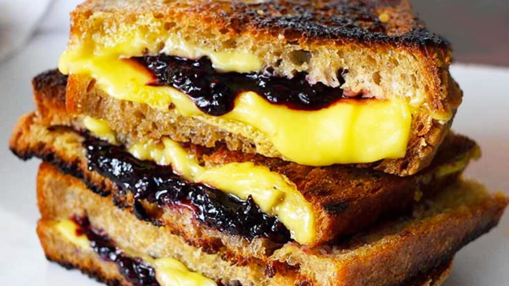 A close up of a stacked Blackberry Grilled Cheese Sandwich on a white platter.