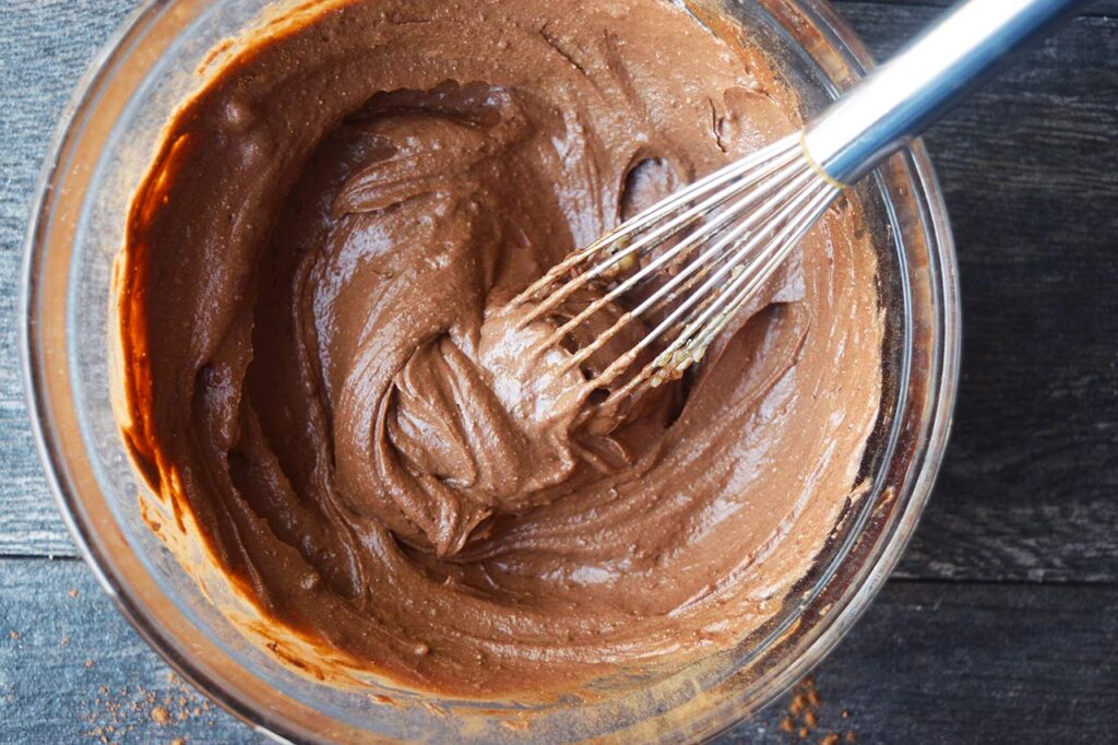 Brownie batter dip ingredients whisked together in a glass mixing bowl.