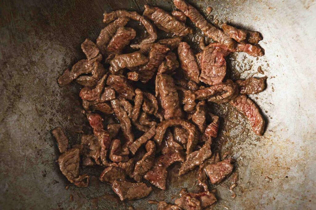 Browned beef pieces in a wok.