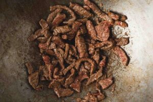 Browned beef pieces in a wok.