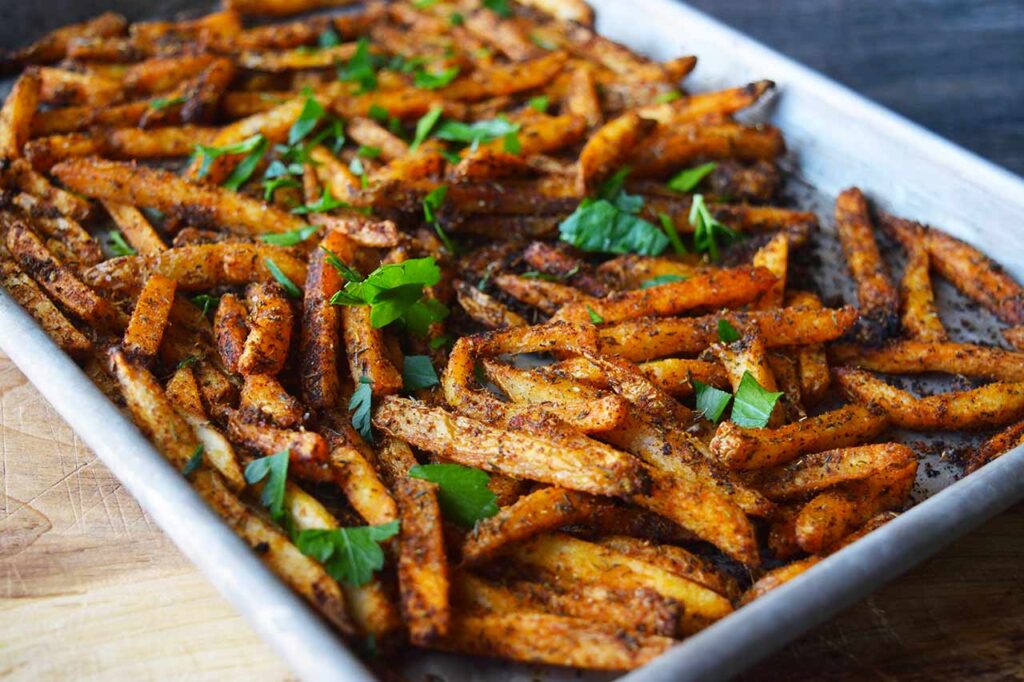 A side view of a baking sheet full of Cajun Fries.