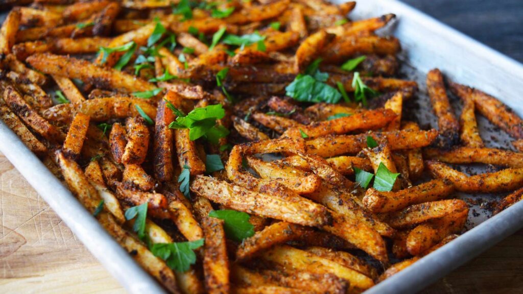 A side view of a baking sheet full of Cajun Fries.