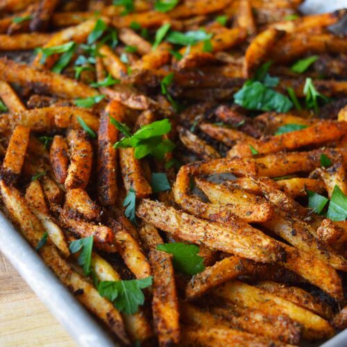 A baking sheet full of Cajun Fries topped with fresh, chopped parsley.