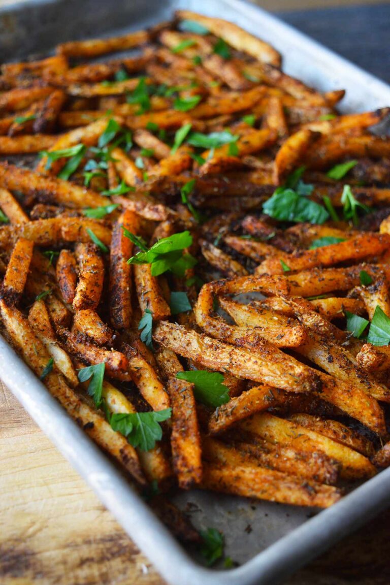 A baking sheet full of Cajun Fries topped with fresh, chopped parsley.