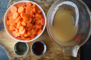 Ingredients for this dill carrots recipe collected in individual containers sitting on a cutting board.