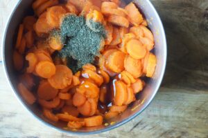 Sweetener added to dill and cooked carrots in a pot.