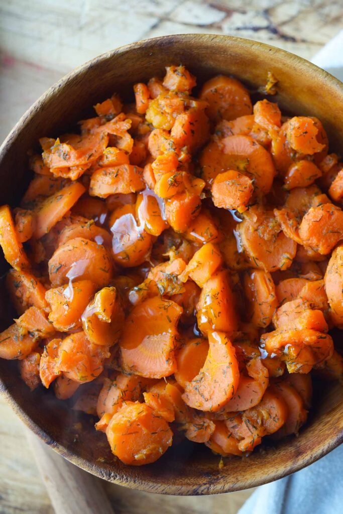 An overhead view of a wood bowl filled with dill carrots.