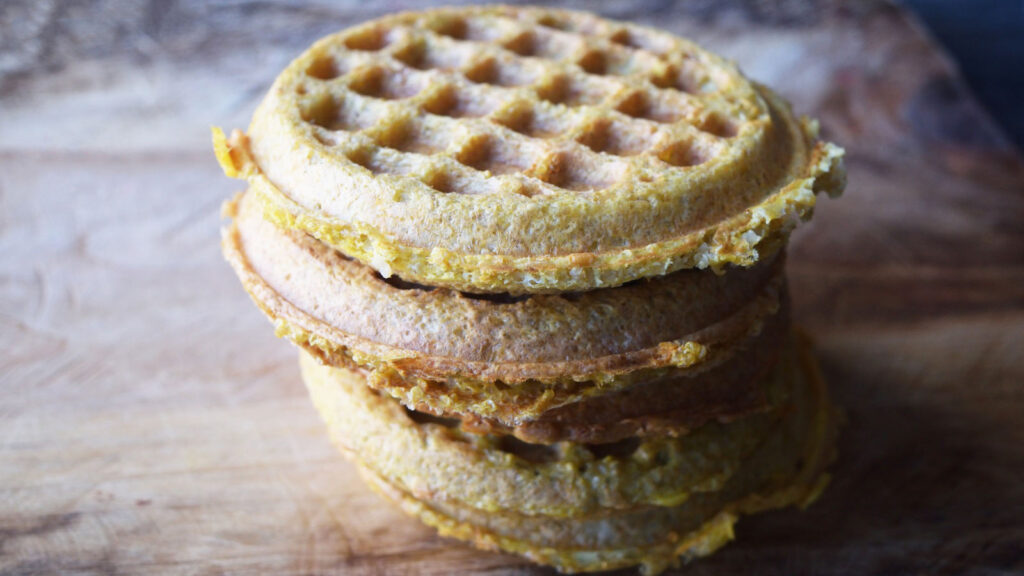 A stack of Gluten-Free Burger Buns on a wooden cutting board.