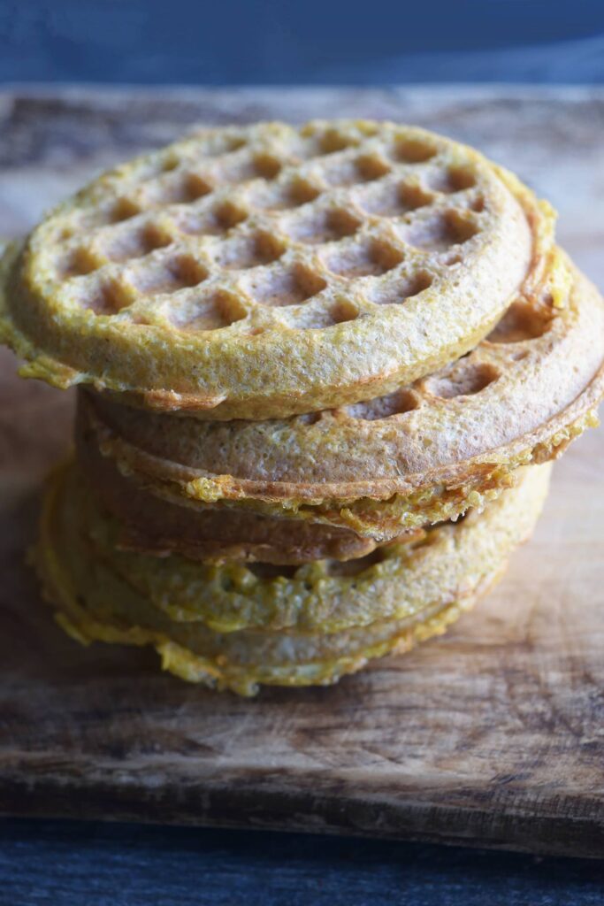 An offset stack of Gluten-Free Burger Buns on a wooden cutting board.