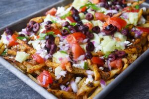 Side view of a sheet pan filled with loaded Greek fries.