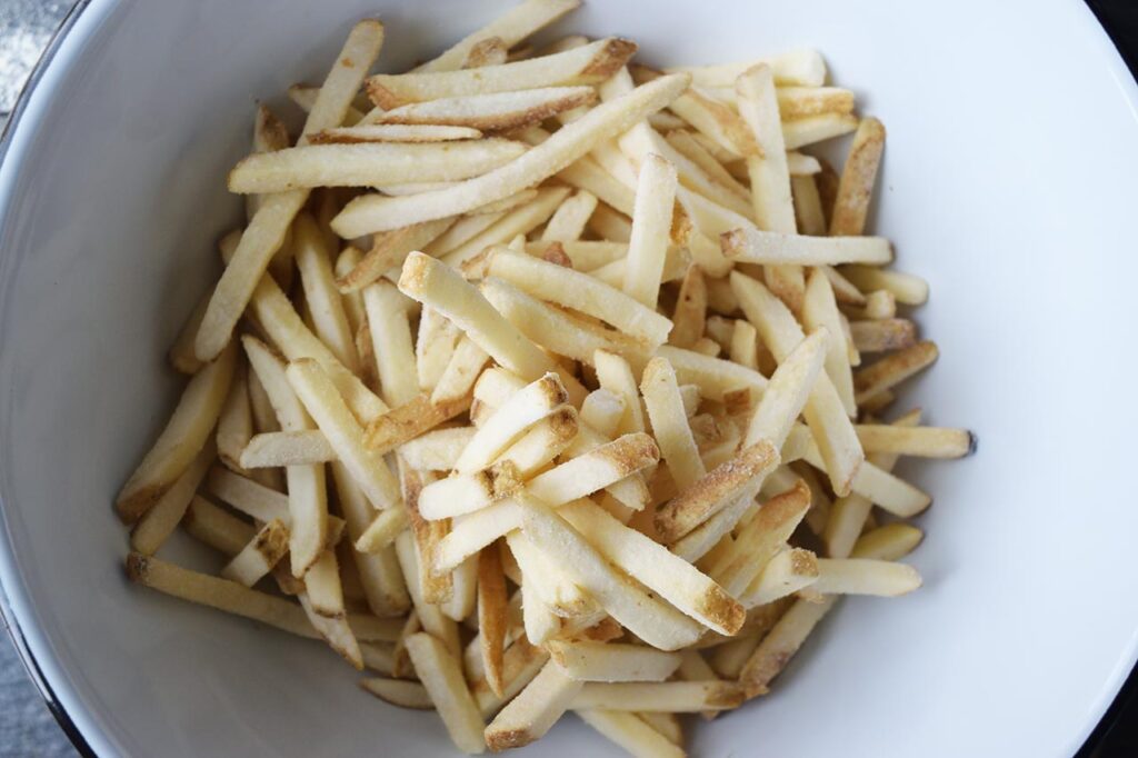 Cut fries in a mixing bowl.