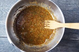 Oil and spices mixed together in a metal mixing bowl.