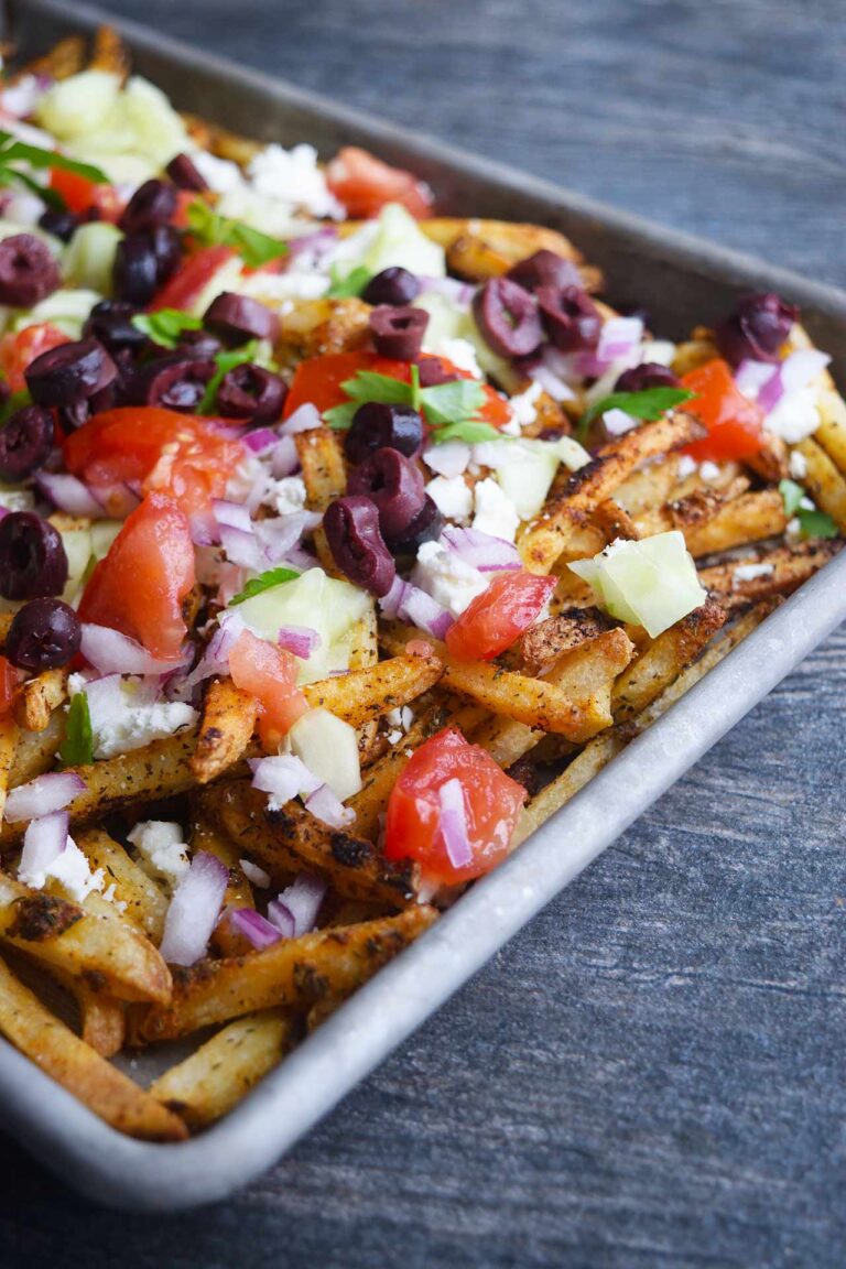 A side view of a sheet pan filled with Greek fries.