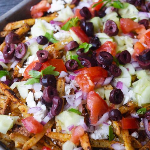 Loaded Greek fries in a sheet pan.