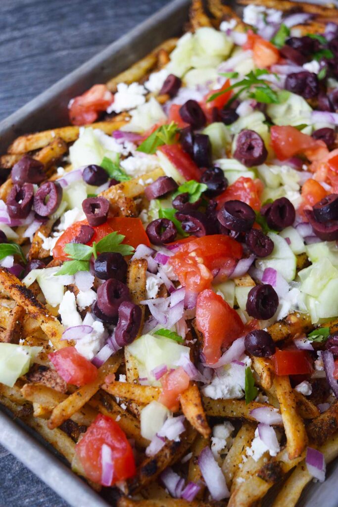 Loaded Greek fries in a sheet pan.