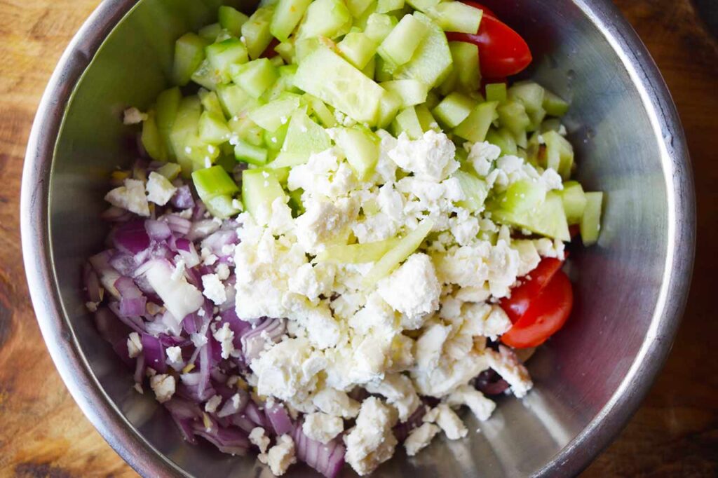 A mixing bowl holding the Greek Chicken Salad ingredients.
