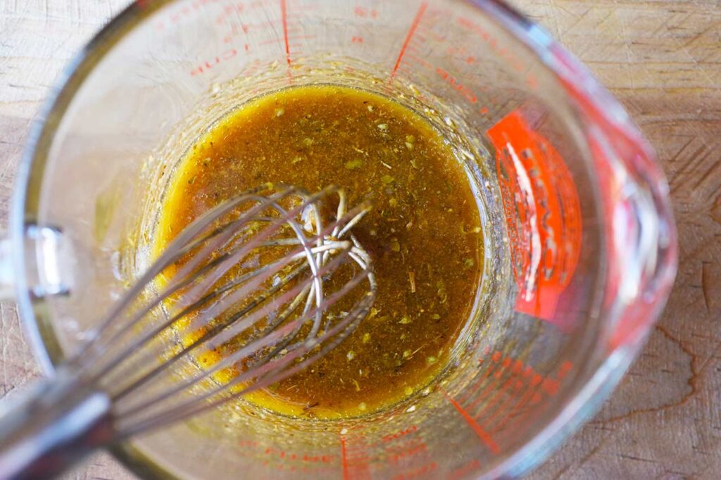The mixed dressing in a measuring cup with a whisk.