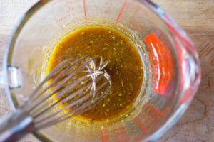 The mixed dressing in a measuring cup with a whisk.