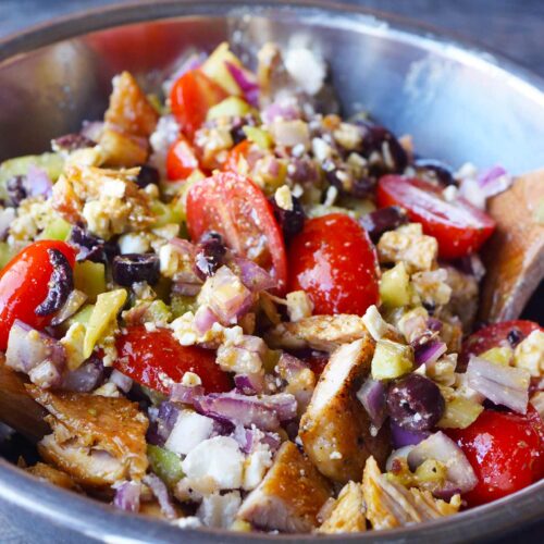 A metal mixing bowl filled with Greek Chicken Salad.
