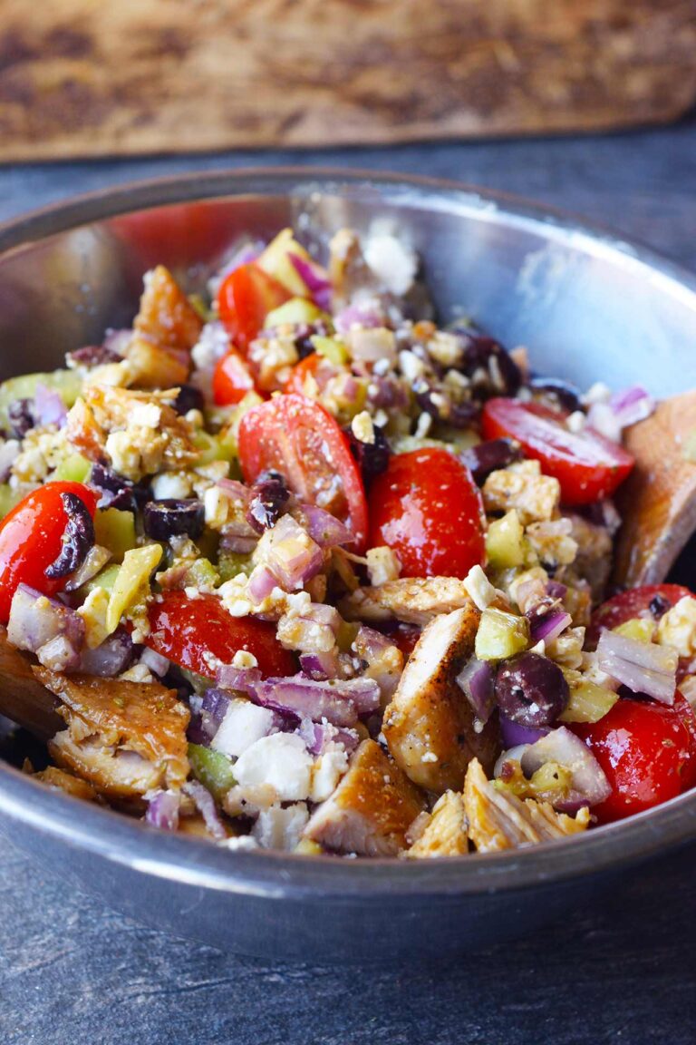 A metal mixing bowl filled with Greek Chicken Salad.