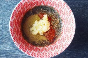 Oil, dried herbs, and pressed garlic in a small bowl.