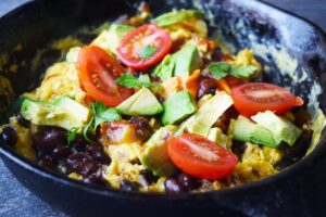 A side view of a black skillet filled with Mexican Scrambled Eggs.