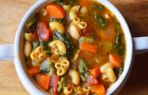 An overhead view of a white crock filled with Pasta Fagioli.