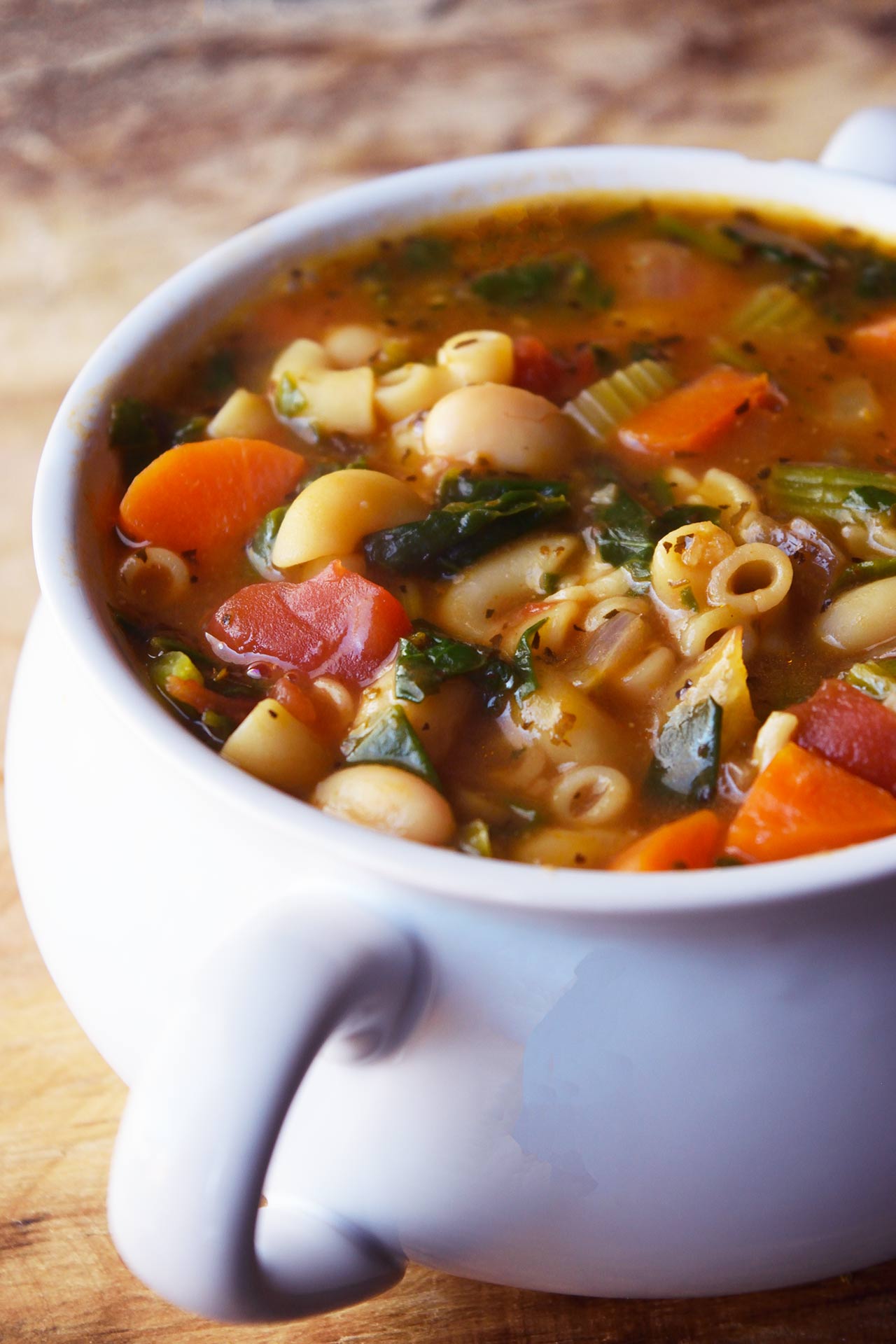 A side view of a white crock filled with Pasta Fagioli.