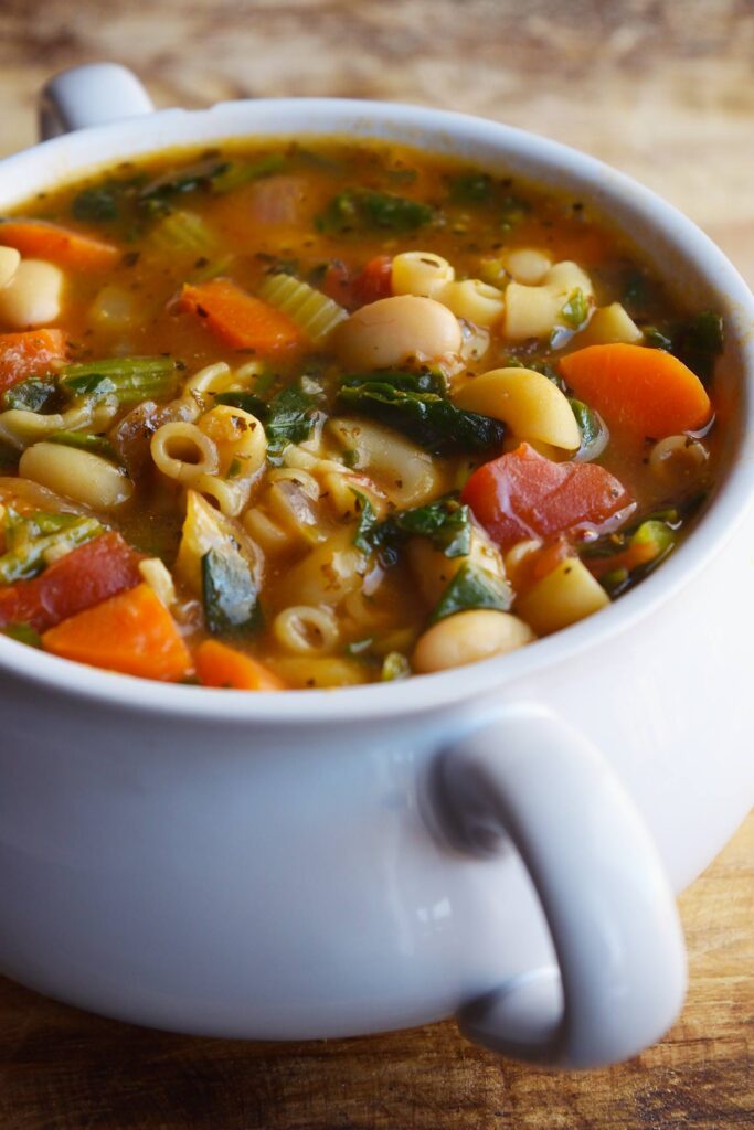 A white crock filled with Pasta Fagioli.