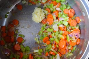 Saut&eacute;d veggies with minced garlic added, in a large soup pot.