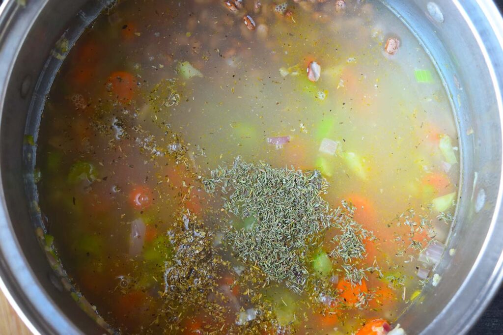 Broth added to soup ingredients in a large soup pot.
