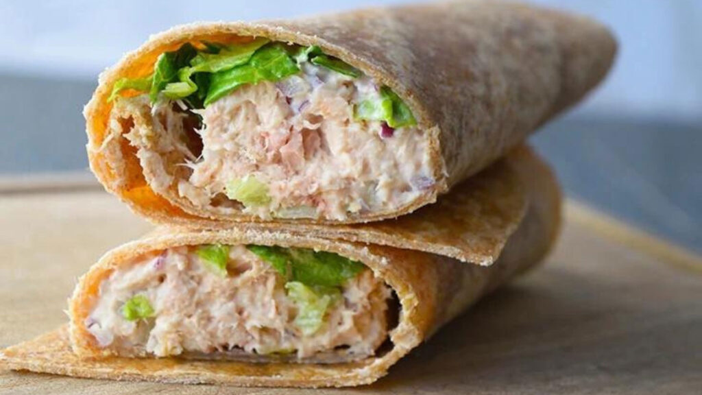 A cut and stacked tuna wrap on a wood cutting board.