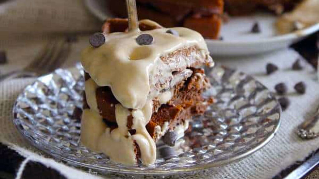 A portion of a stack of chocolate waffles with peanut butter sauce drizzled over the top.