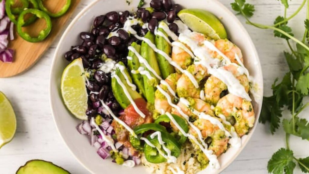An overhead view of a bowl of cilantro lime shrimp with dressing drizzled over the top.