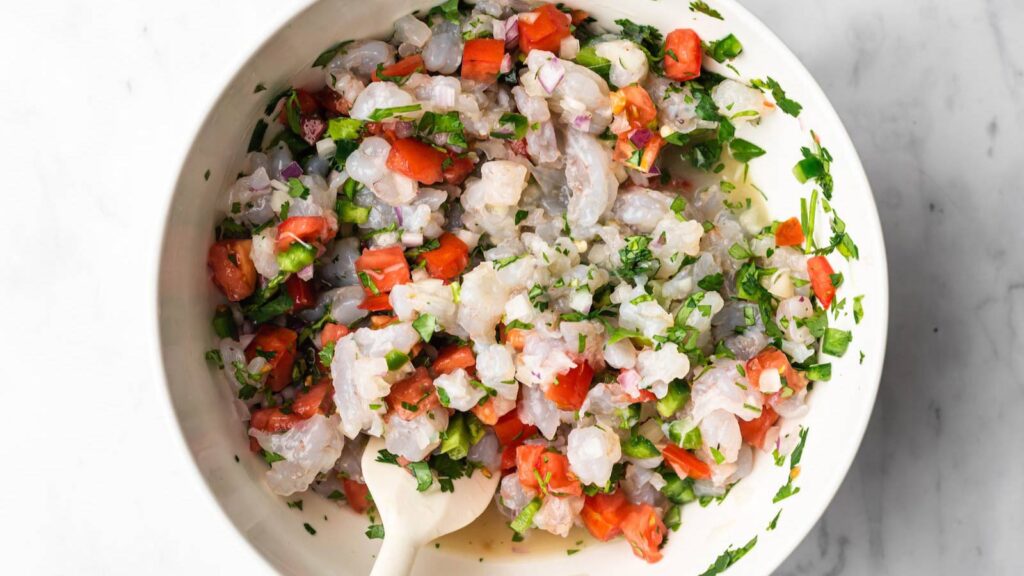 An overhead view of a white bowl filled with shrimp ceviche.