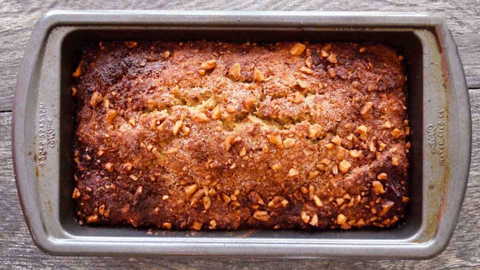 A loaf pan with a loaf of apple bread in it.