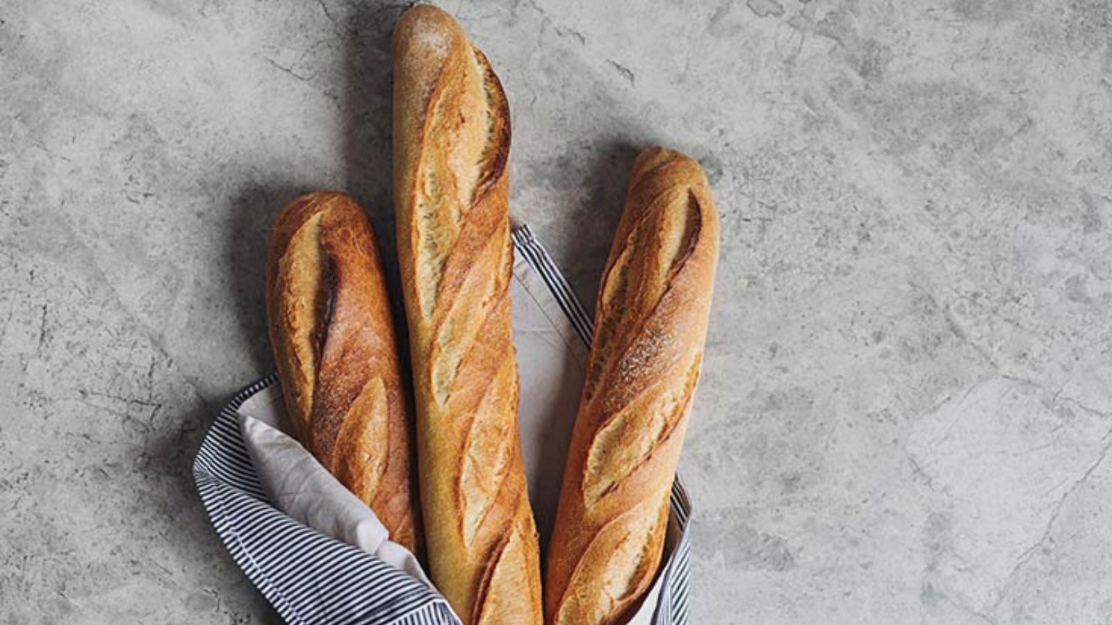 Three baguettes wrapped in a blue towel.