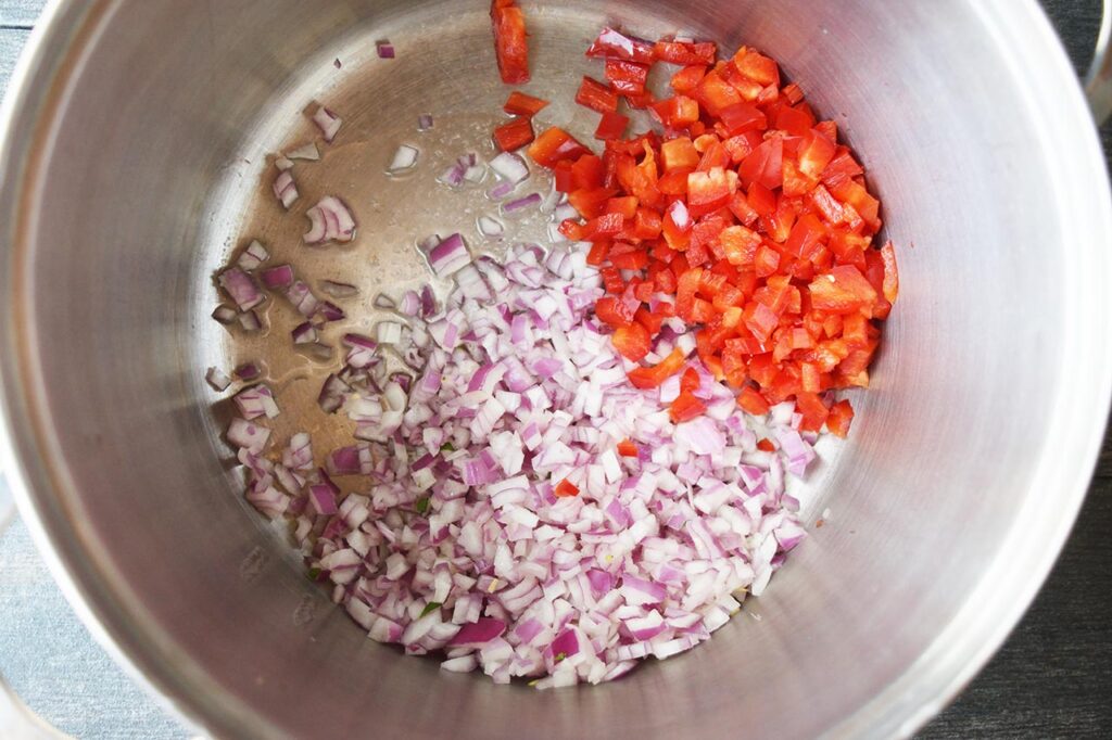 Chopped red bell pepper and red onion in oil in a large soup pot.