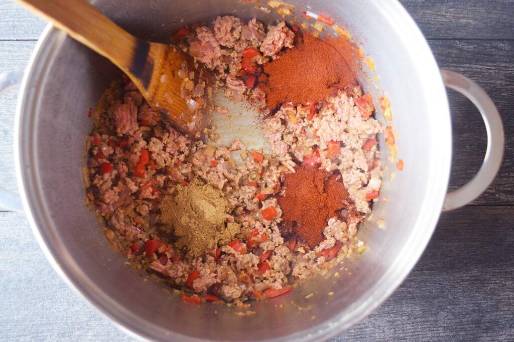 Spices added to browned meat in a large soup pot.