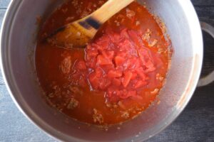 Diced tomatoes and broth added to a soup pot of browned meat and sautéd vegetables.