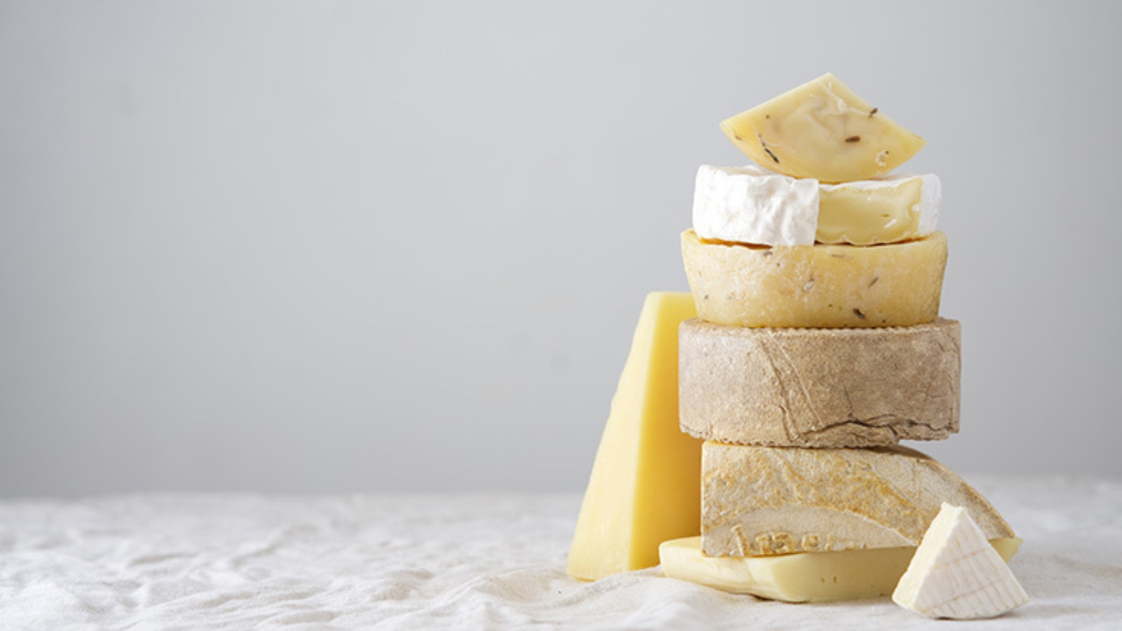 A stack of various cheeses on a white table.