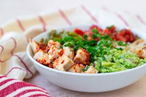 A side view of a white bowl filled with avocado chicken salad.