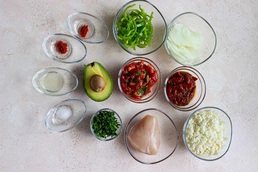 Ingredients for a Chicken Avocado Salad collected in individual bowls.