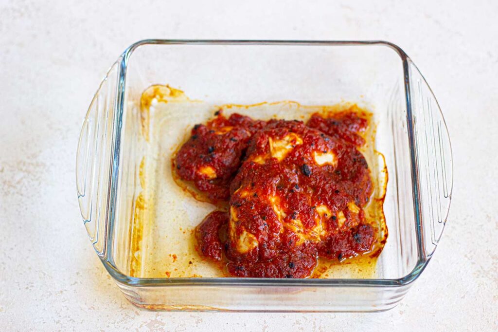 A baked chicken breast cooked in blended roasted red pepper.
