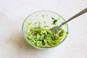 The avocado mix blended with a fork in a bowl.