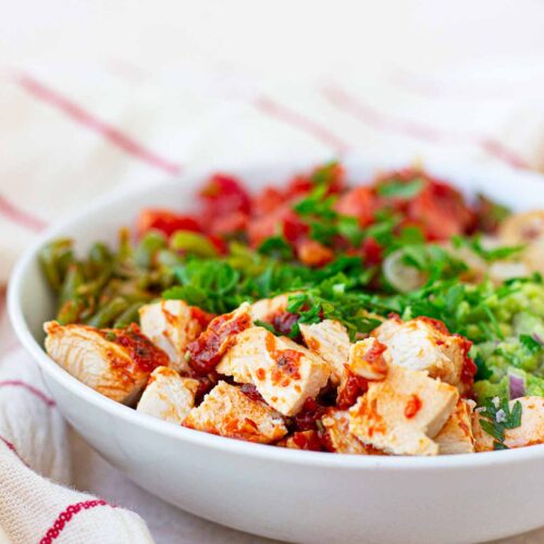 A side view of a white bowl filled with Avocado Chicken Salad.