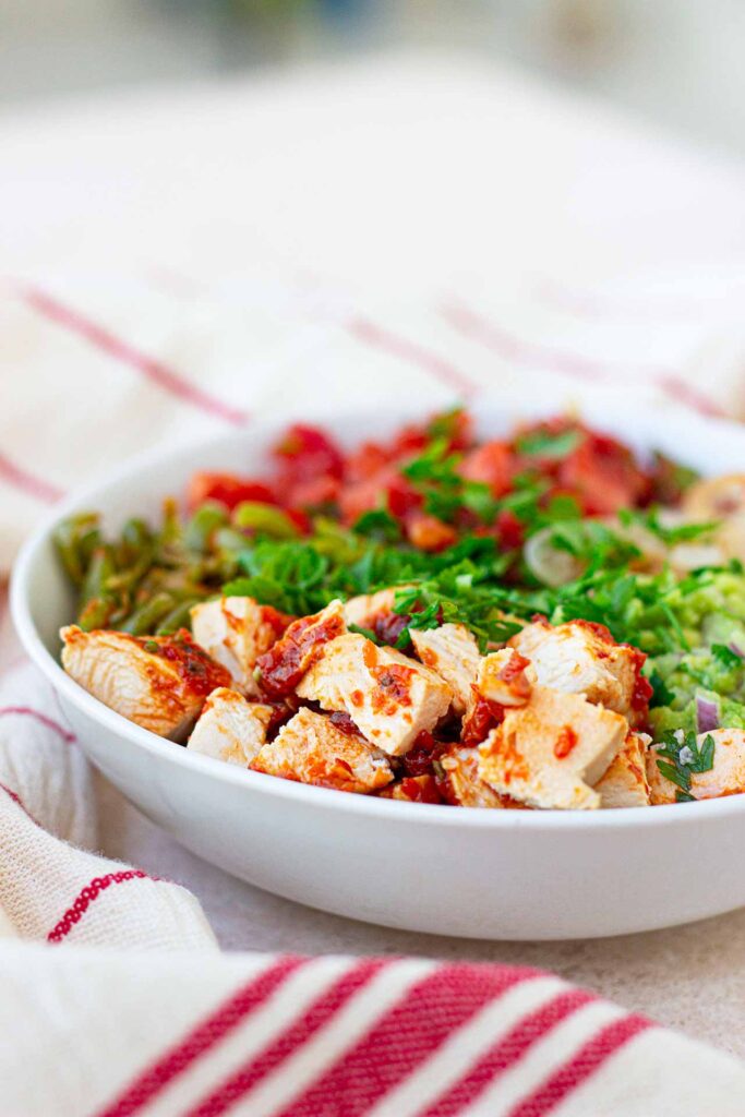 A side view of a white bowl filled with Avocado Chicken Salad.